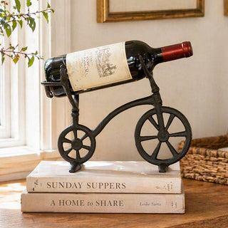 Vintage tricycle wine rack holding red wine bottle on bar cart
