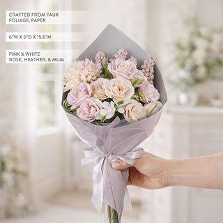 Hand holding faux pink rose bouquet wrapped in grey paper with satin bow showing dimensions text