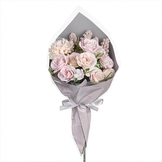Full view of artificial pink rose bouquet in grey paper wrapping on white background