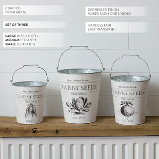 Three vintage-style white metal Farm Seeds buckets