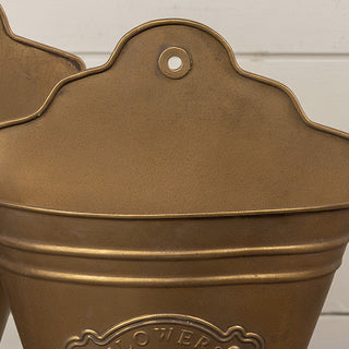Close-up of scalloped back plate and nail hole on distressed gold metal wall bucket planter