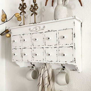 Decorative carved wood detail on distressed white cabinet