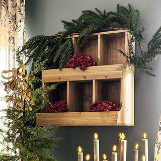 Close-up of rustic wooden wall cubby organizer styled with greenery and burgundy flowers for seasonal home décor