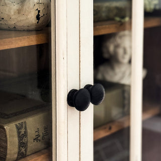 Close-up of black round knobs on distressed white wood cabinet