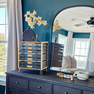 Navy accent cabinet beside arched bedroom mirror