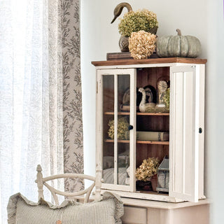 Distressed farmhouse glass cabinet styled with vintage decor