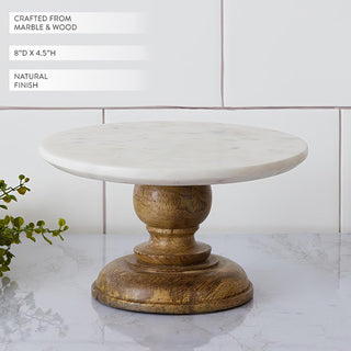 Marble and wood pedestal cake stand with natural finish, shown on a marble countertop with product dimensions 8 inches by 4.5 inches.
