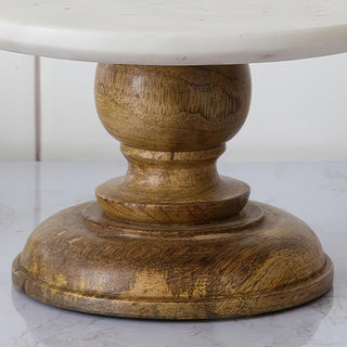 Close-up detail of a natural-finish wooden pedestal base supporting a round marble cake stand for home décor or dessert display.