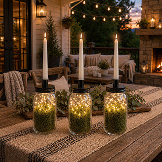 Clear glass mason jar candleholder with black metal lid on rustic outdoor table