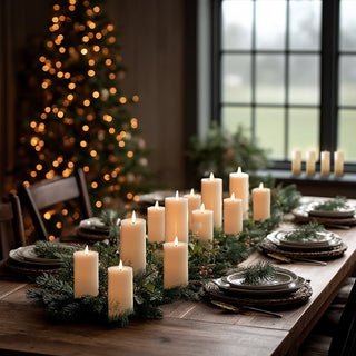 Flameless LED pillar candles arranged on Christmas dinner table with evergreen garland and place settings