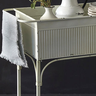 Close-up of distressed white painted metal corrugated panel detail on vintage bar cart with arched frame