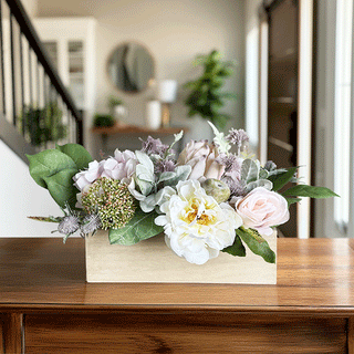 Faux floral centerpiece with white peonies and blush roses in natural wood box on dining table