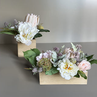 Side-by-side comparison of square and rectangular faux floral centerpieces in wooden boxes