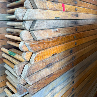 Close-up view of stacked vintage wooden folding chairs showing natural aged wood grain and hardware details