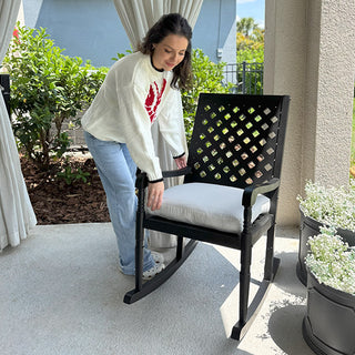 Woman adjusting cushioned black porch rocking chair