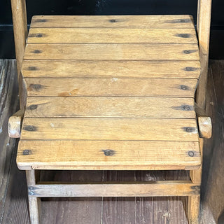 Close-up of the seat area on a vintage wooden folding chair showing the aged wood texture and joinery