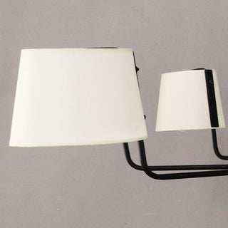 Close-up detail of black iron chandelier arm with white tapered fabric shade