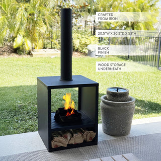 Black iron chiminea with tall chimney and wood-storage shelf displayed on a patio beside a modern stone water fountain.