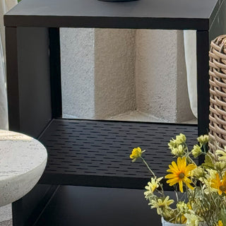 Close-up of modern black outdoor fireplace showing vented base and slotted fire grate design.