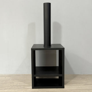 Minimalist black chiminea fireplace photographed indoors against a gray wall for product display