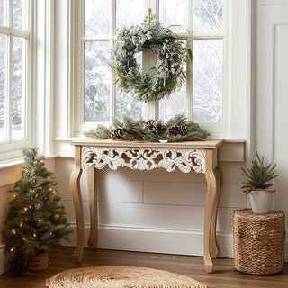 French Provincial console table with ornate carved scroll detail in natural wood finish displayed in bright entryway with Christmas wreath and holiday decor