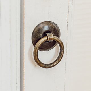 Antique brass ring pull hardware on white cabinet door