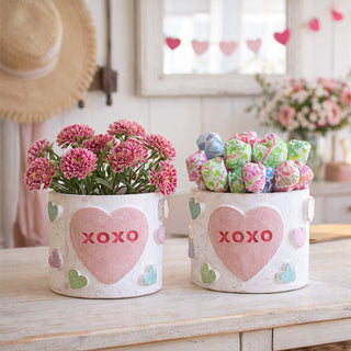 Two clay XOXO conversation heart containers on marble kitchen counter one filled with wrapped candy one with pink flowers farmhouse Valentine decor