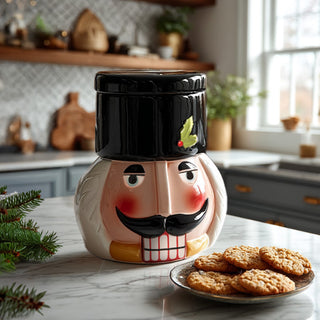 Classic dolomite nutcracker cookie jar with black hat lid and holly accent displayed on white marble kitchen counter with fresh-baked cookies and Christmas greenery