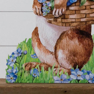 Full view of standing wooden bunny yard stake with hydrangea basket on wooden surface against white shiplap background