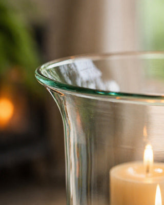 Glass candle holder with a lit candle against a blurred background