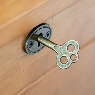 Skeleton key in decorative keyhole showing vintage hardware detail on secretary desk