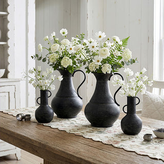 Black rustic metal ewers with white floral arrangement