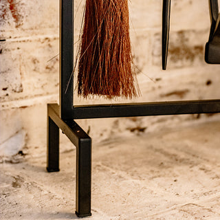 Close-up of the fireplace tool set base and bristle broom, highlighting sturdy iron frame and natural bristles for fireplace maintenance.