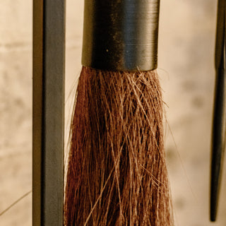 Macro shot of bristle broom head from fireplace tool set, showing texture and quality craftsmanship suitable for rustic home decor.