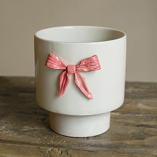Modern pedestal ceramic pot with decorative pink bow accent perfect for Christmas greenery succulents or year-round home decor displayed on rustic wood table