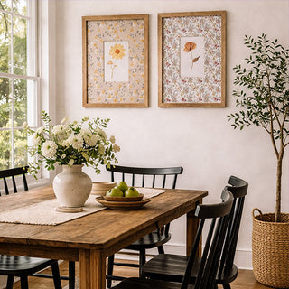 Two wooden framed botanical prints with pressed flower art and floral pattern mattes on dining room wall