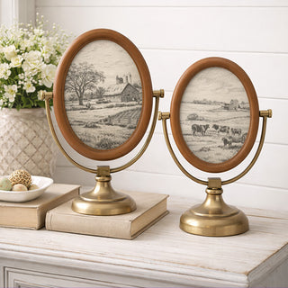 Two oval picture frames on stands with pastoral scenes, placed on a surface with a white background. Oval Photo Frame, Set of 2 | Antique Brass Stand Vintage Tabletop Picture Frame