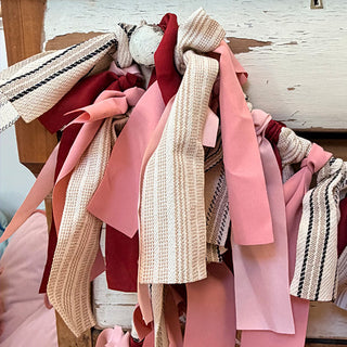 Detail shot of handcrafted fabric tassel garland showing pink burgundy ticking stripe ribbon textures