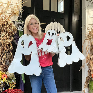 Woman holding three metal ghost Halloween decorations