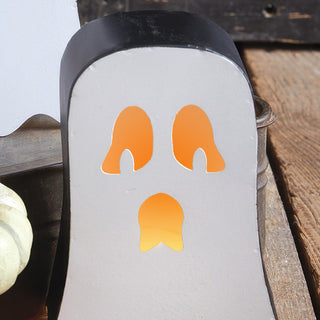 Close-up of small ghost metal candle holder with glowing cut-out face