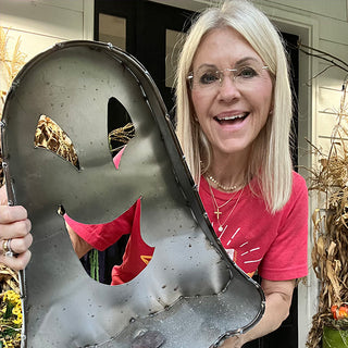 Close-up of smiling woman holding metal ghost Halloween decoration