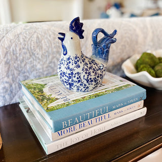 Decorative blue and white ceramic chicken on a stack of books with a blurred background