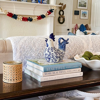 Decorative setup with books, ceramic ducks, and a candle on a coffee table in a living room.