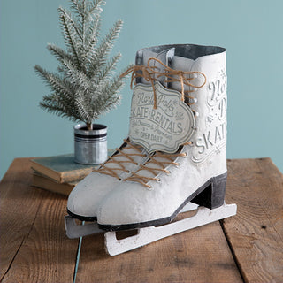 Pair of vintage-style white metal ice skates with North Pole Skate Rentals sign and jute string laces, set on a rustic wooden table