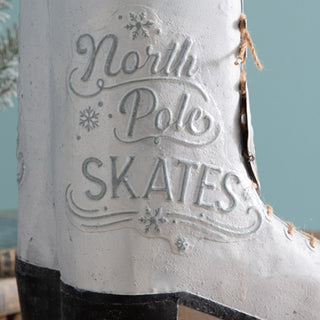 Detail of North Pole Skates embossed lettering on distressed white metal ice skate Christmas decoration with rustic finish