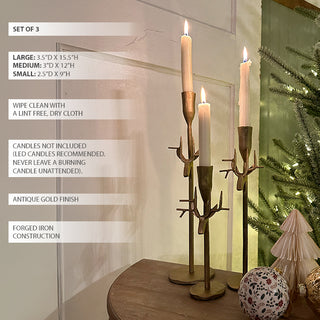 Gold metal reindeer-antler taper candle holders set of three displayed on a wooden surface beside holiday décor, with product size and care instructions shown on the left