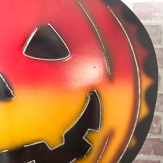 Detailed view of the carved face on a gradient metal jack-o’-lantern pumpkin Halloween decoration