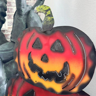 Close-up of top pumpkin with green stem on a stacked metal jack-o’-lantern Halloween decoration