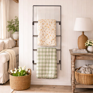  Farmhouse wall mounted blanket ladder displaying floral quilt and green gingham throw in cozy living room with white shiplap walls