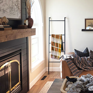 Cozy living room with a blanket ladder, fireplace, mirror, and decorative items.